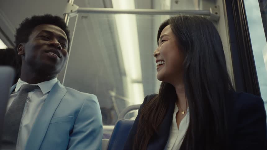 A man and woman laugh and talk on the train