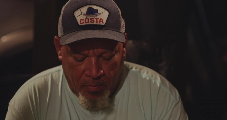 A man wearing a baseball cap is deep in thought as he looks down