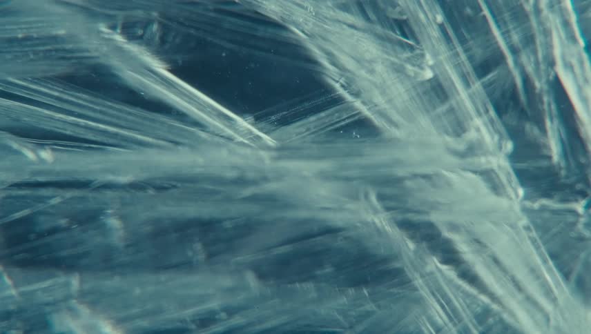 Extreme close up on an abstract transparent liquid with a freezing ice