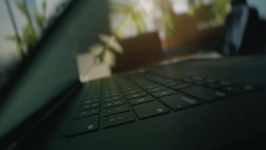 A person types with one hand after opening the laptop