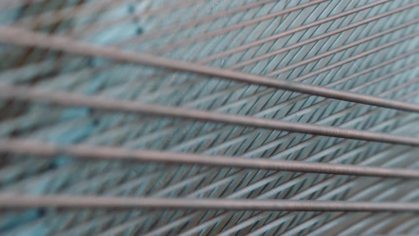Closeup of metal wires arranged parallel in a geometric pattern