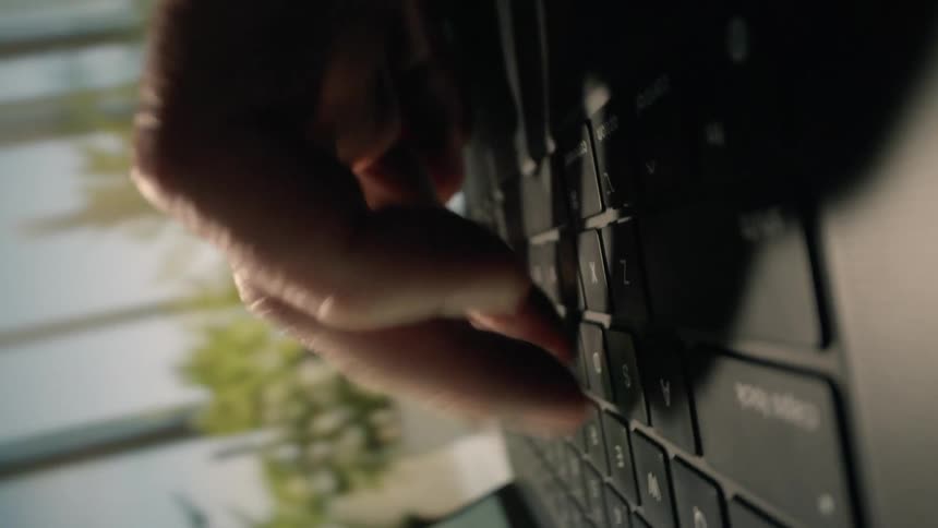 Closeup of a hand typing on a black keyboard