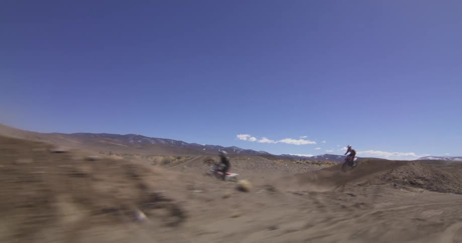 Several people are racing dirtbikes on a desert course