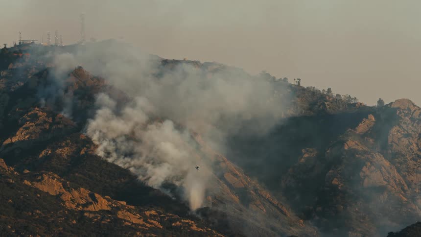A helicopter dumps water on a wildfire