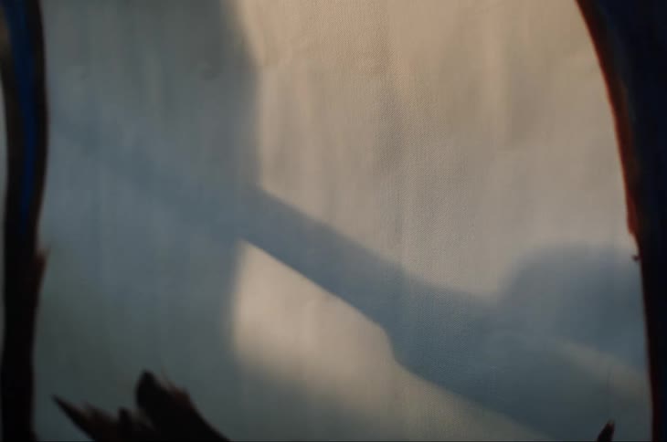 Shadow of an artist mixing paint on a palette cast over the canvas