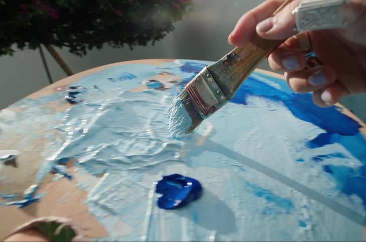 A person is mixing different color paints with a brush