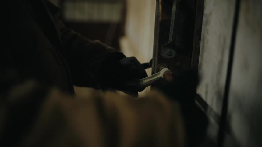 A man unlatches a clamp from a fence