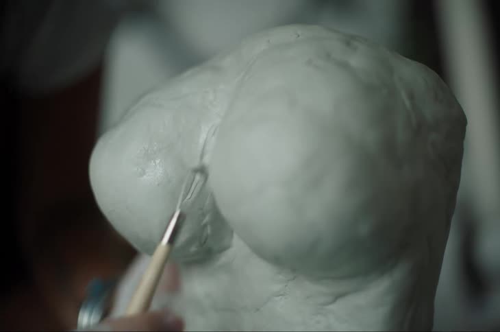 An artist is using a small tool to sculpt