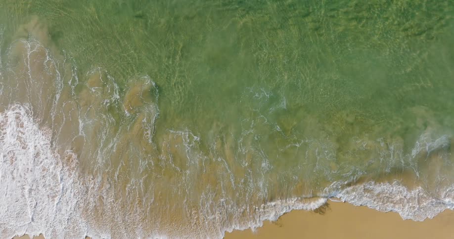 Ocean waves slowly wash up on the shore of a beach