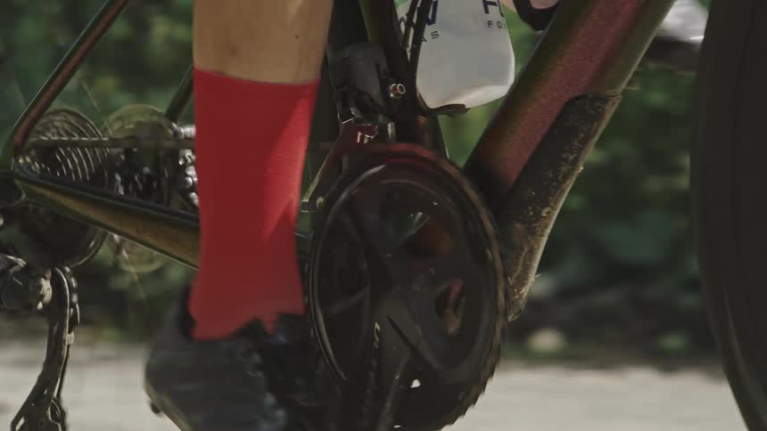 Closeup on the crank in motion of a gravel bike being ridden at high speed on a dirt road