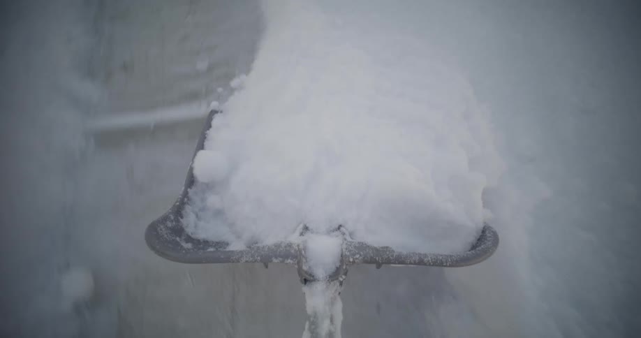 A person shovels snow from a sidewalk