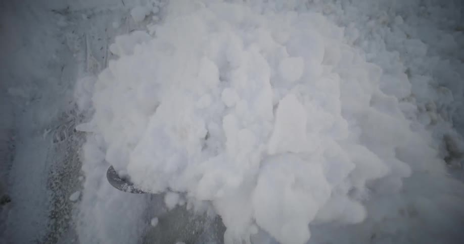 A snow shovel is being used to clear a path covered in snow