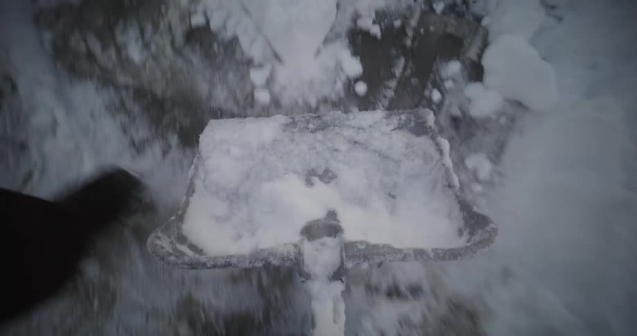 A clip of a person shoveling away ice