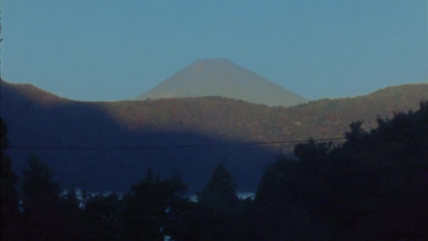 Mount fuji rises against a clear blue sky its peak shrouded in a soft haze