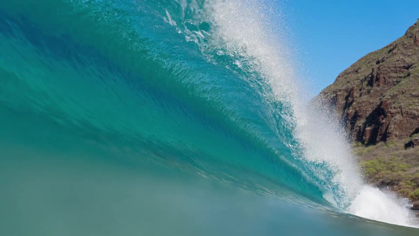 Crystal clear wave in motion captured in closeup with vibrant blue tones and white foam on top
