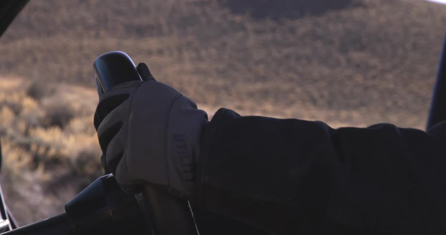 A person with gloves on grips the steering wheel tight
