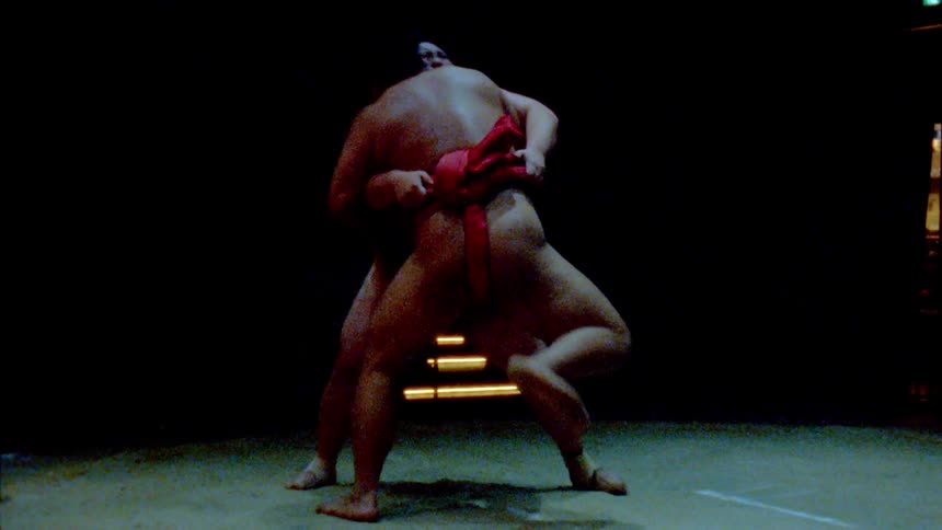 Two sumo wrestlers are battling in the ring
