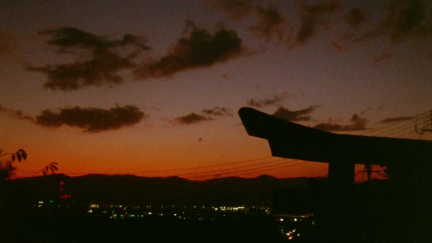 Silhouette of a traditional roof against a vibrant orange and purple sky at sunset
