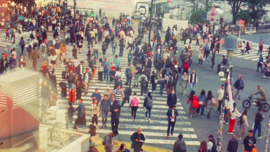 A busy pedestrian crossing at an intersection with a large crowd of people walking in various directions