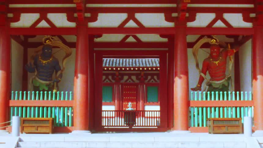 Two imposing guardian figures flank the entrance to a traditional japanese temple standing watch over the stone steps leading to the inner sanctum