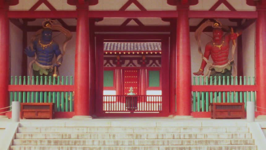 Two imposing guardian figures flank the entrance to a traditional japanese temple standing watch over the stone steps leading to the inner sanctum