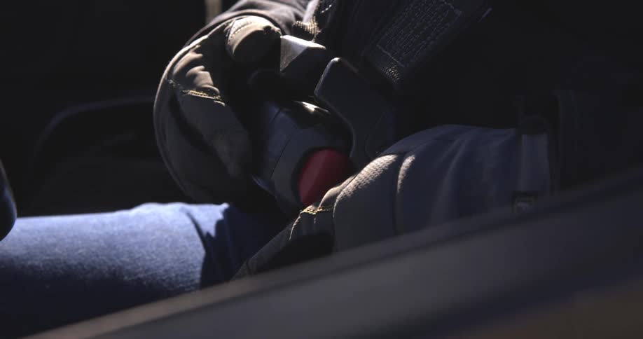 A man wearing gloves buckles his seatbelt