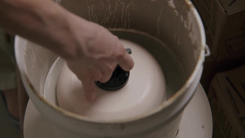A woman lowers some pottery into a bucket of water