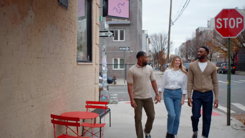 Three friends walking on the sidewalk of an urban city