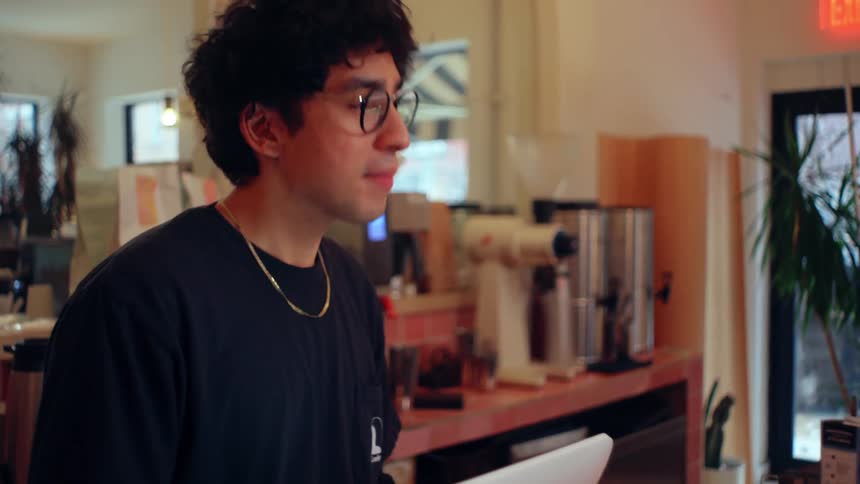 Male cashier takes an order at a cafe counter
