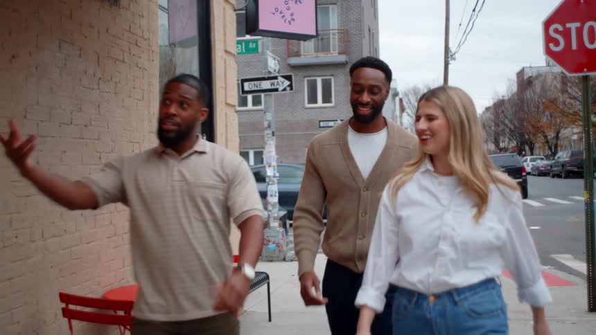 Three people walking down the street turn toward a building