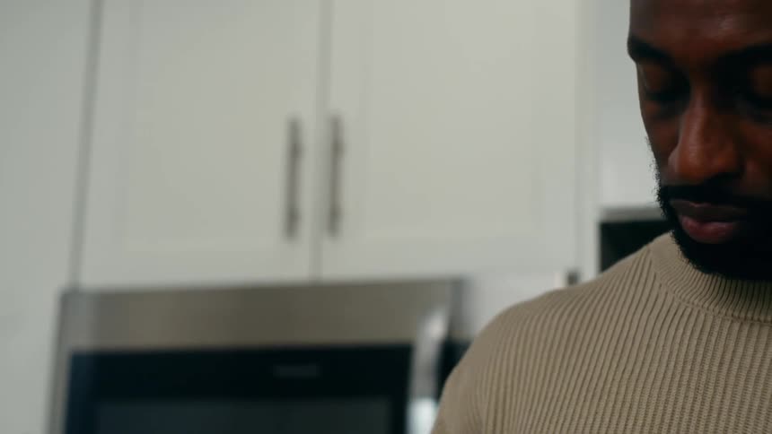 Man cooks while standing in a kitchen with white cabinets
