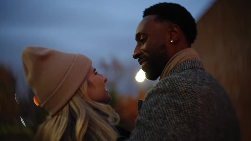 Couple cuddles while standing outdoors on a winter evening