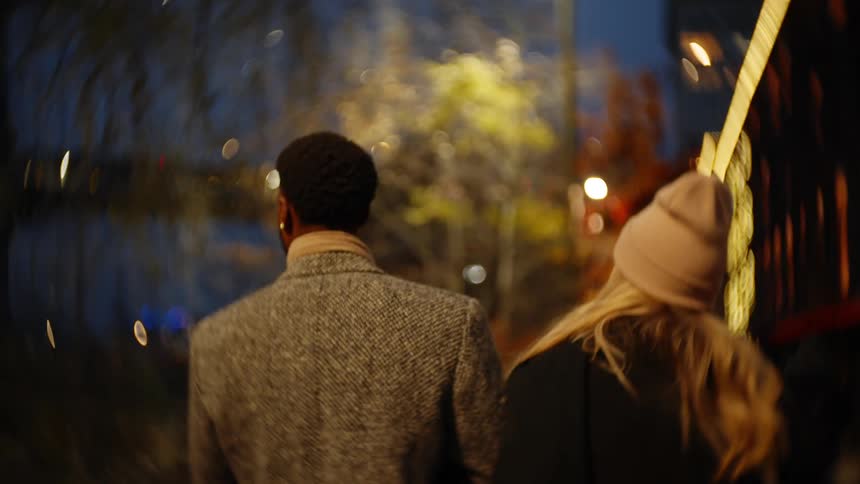 A couple walk through the city at night