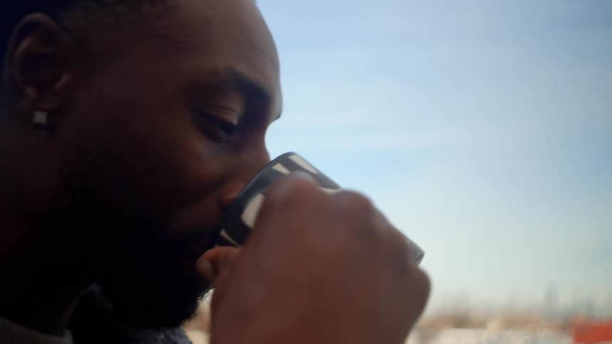 Friends clink cups while drinking a warm beverage on their balcony