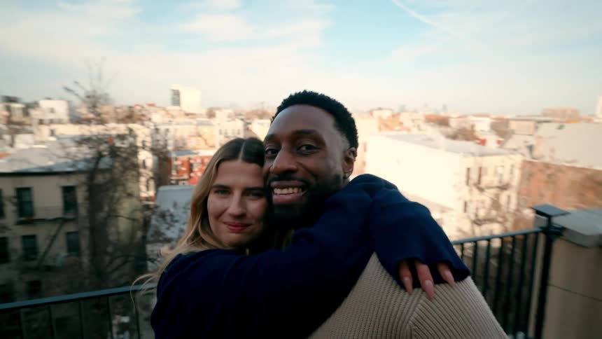 A man and woman are hugging and smiling on the balcony