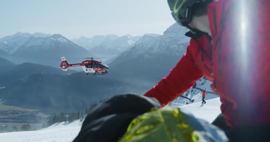 A helicopter is landing on the mountain to help an injured man