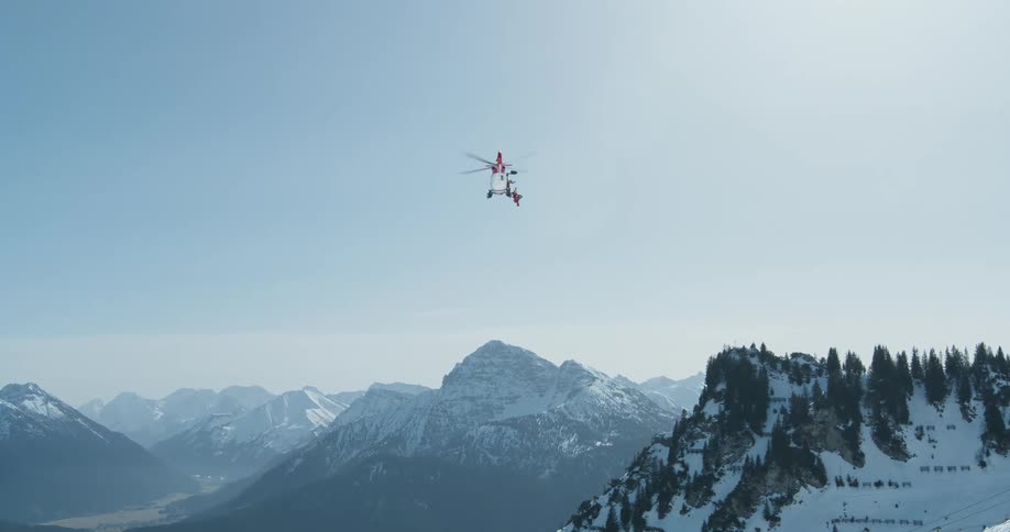 Helicopter flying over a snowy mountain valley