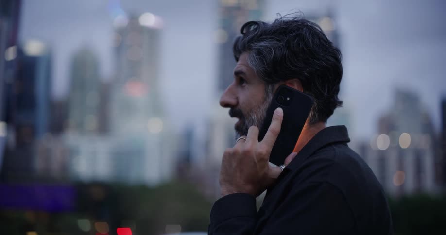 A man is talking on his cell phone in front of the skyline