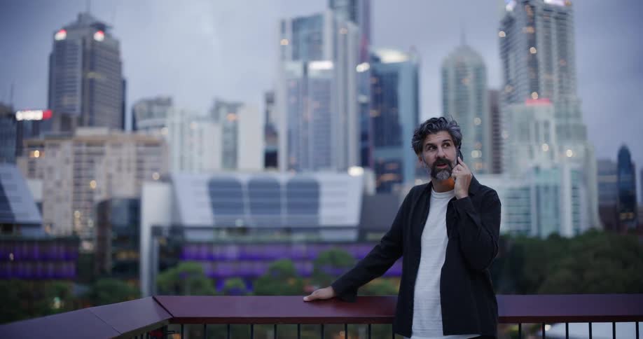 A man is on the balcony talking on his cell phone