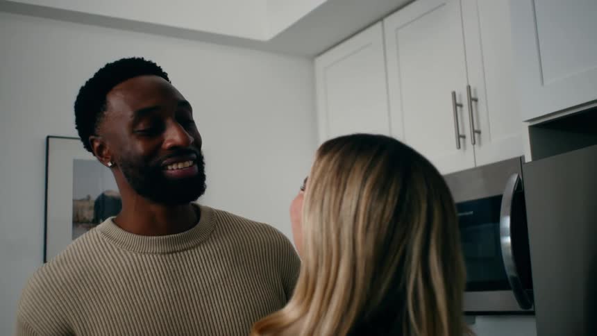 A woman feeds a man a piece of tomato and they kiss