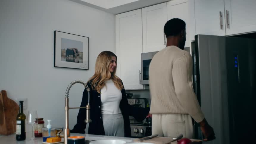 A man and a woman interact in a modern kitchen preparing food together