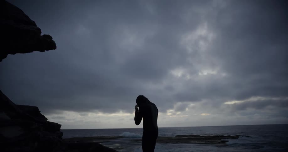 A man puts on a wet suit on the beach