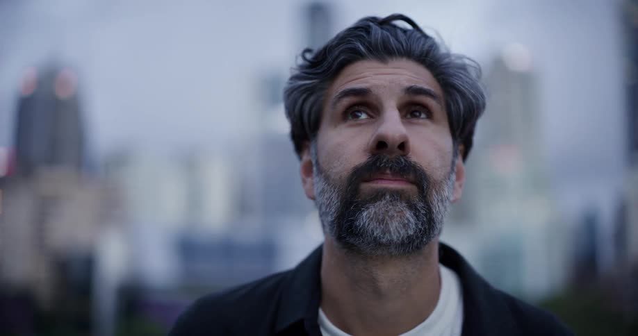 A man is standing outside in a city looking around