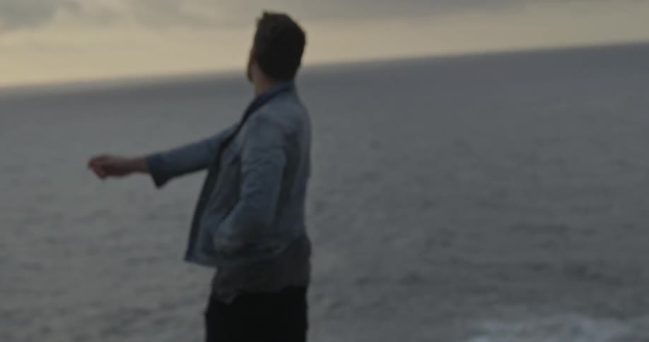 A man throws a rock towards the ocean