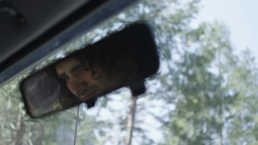 Man can be seen in rear view mirror driving
