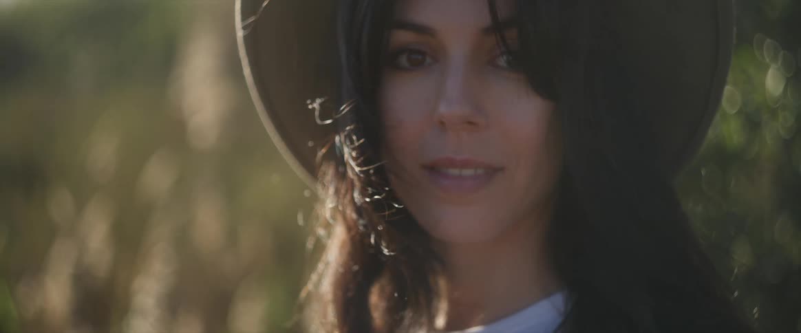 Woman wearing a sunhat smiles while outdoors on a windy day