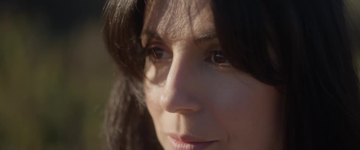 Portrait of a young black haired woman opening her eyes while standing in a field