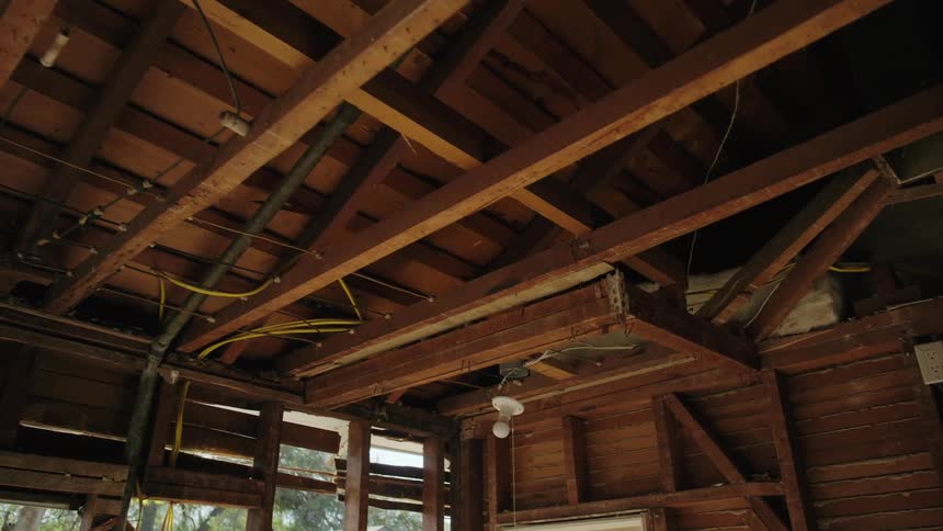 A view of the interior of a house under construction showing exposed wooden beams and wires
