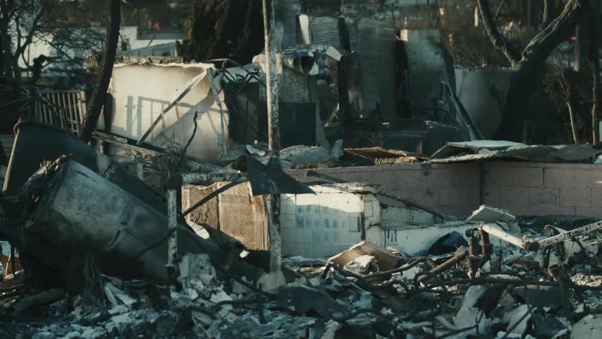 The aftermath of a fire showing a house reduced to charred debris and rubble