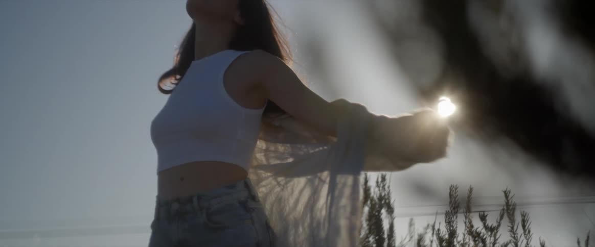 A woman is spinning around under the sun